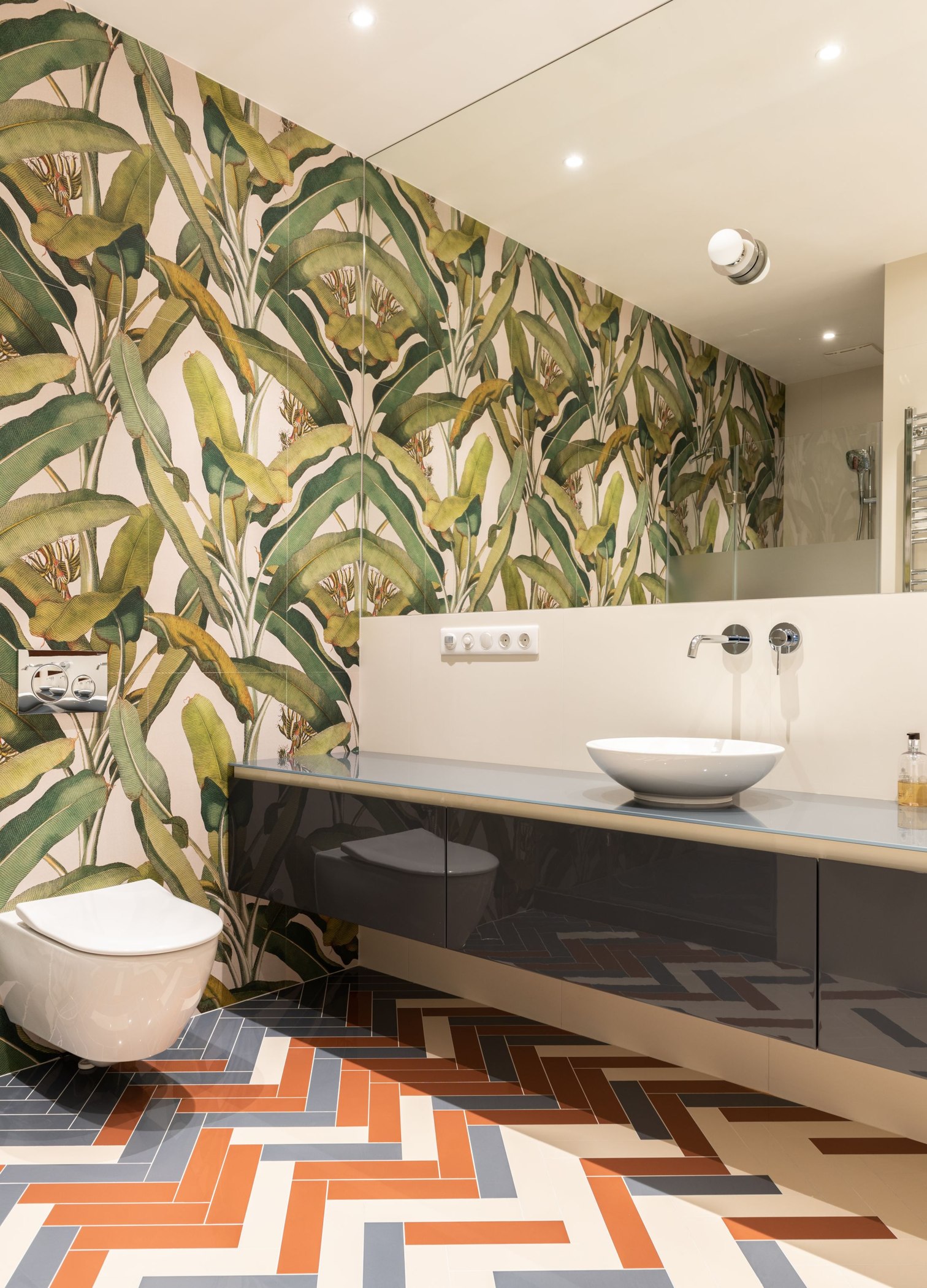 Large green botanical wallpaper leaves above a contemporary bathroom vanity