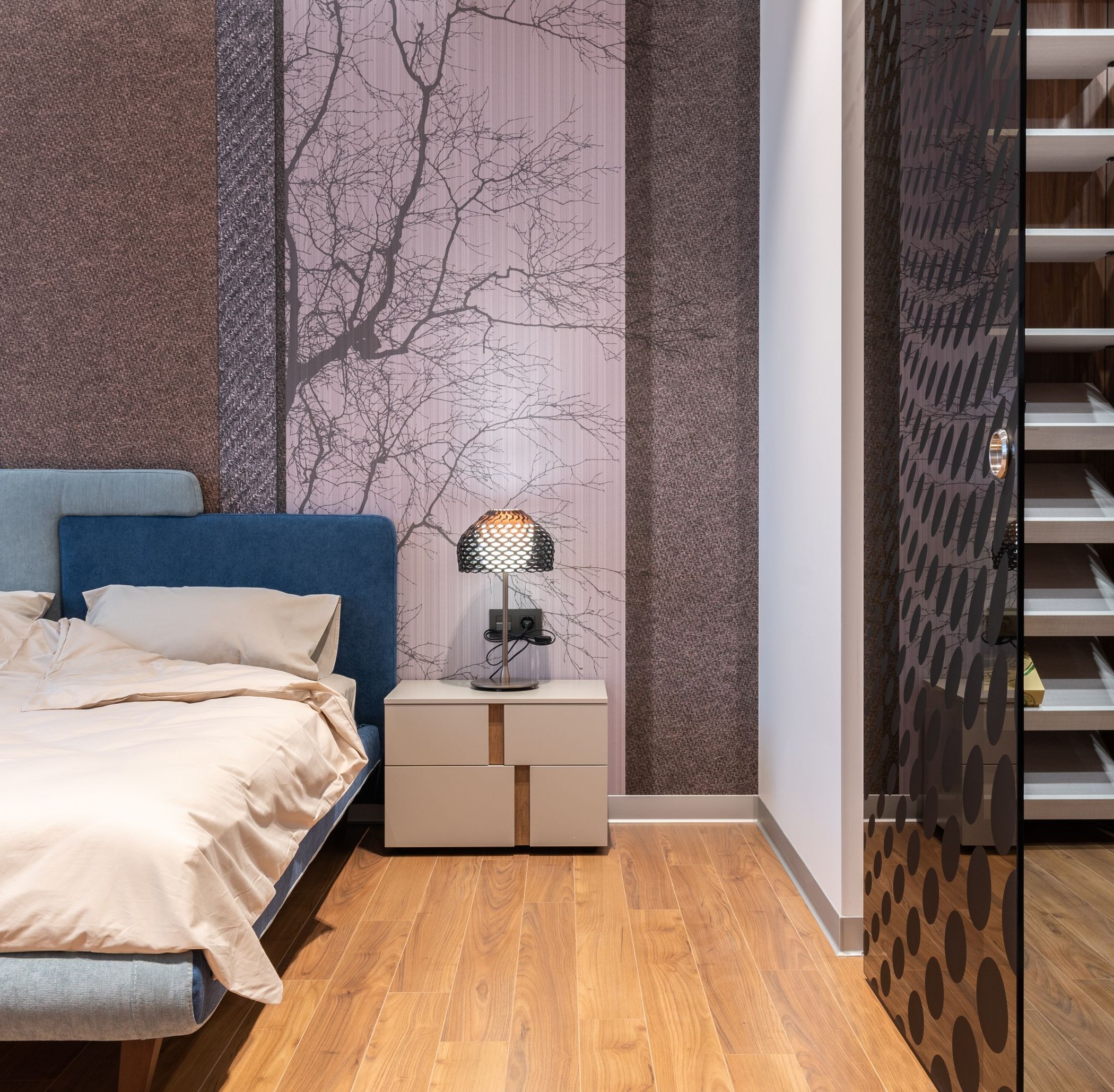 Hospitality bedroom featuring textured wallcovering and a delicate branch-pattern wallpaper panel