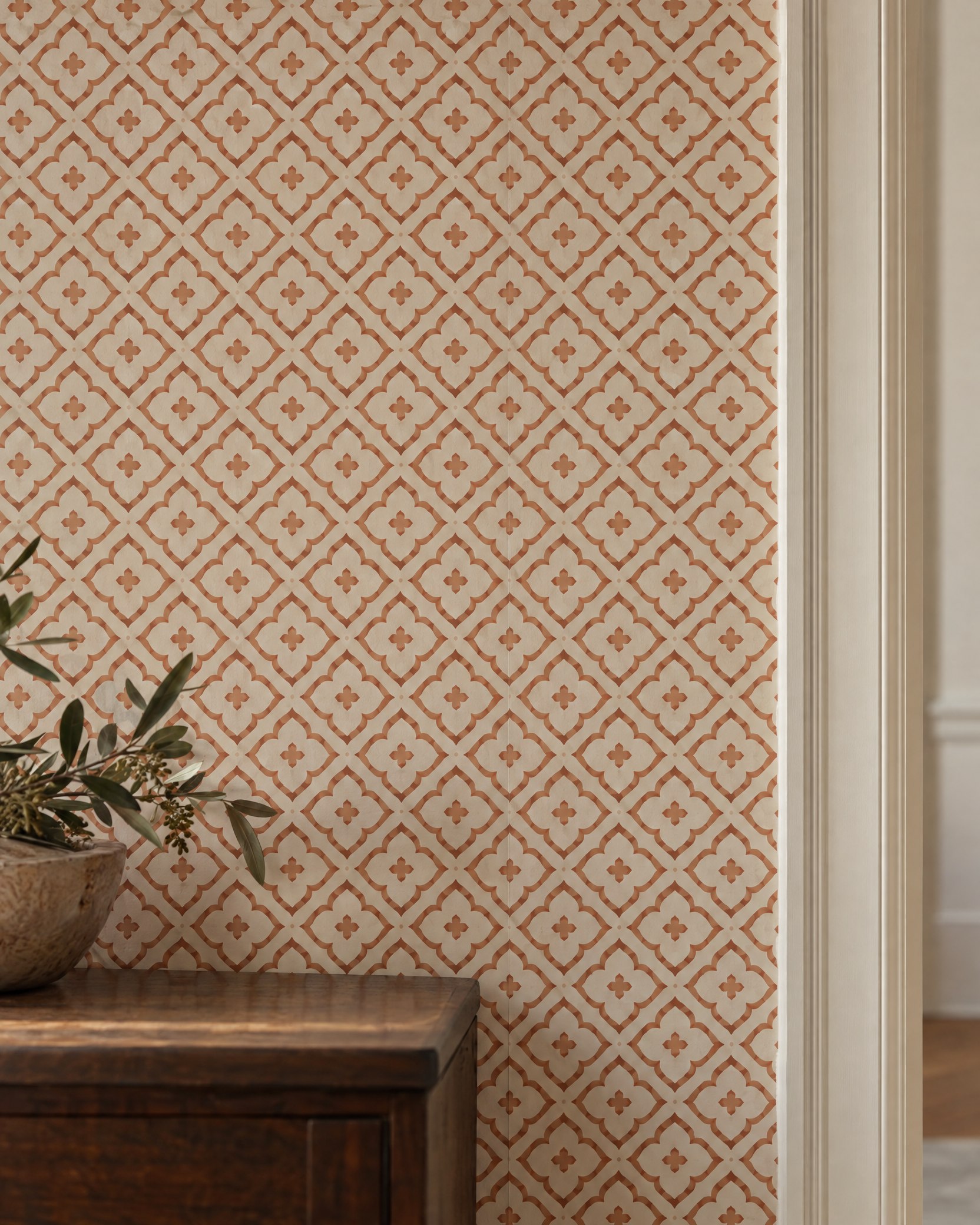 Aligned terracotta lattice wallpaper with a cleanly finished edge beside an ivory door casing